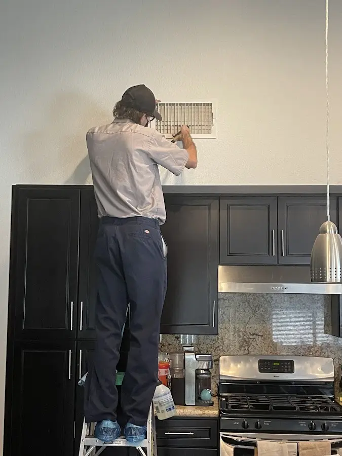 Technician inspecting an air vent during HVAC service in Buford